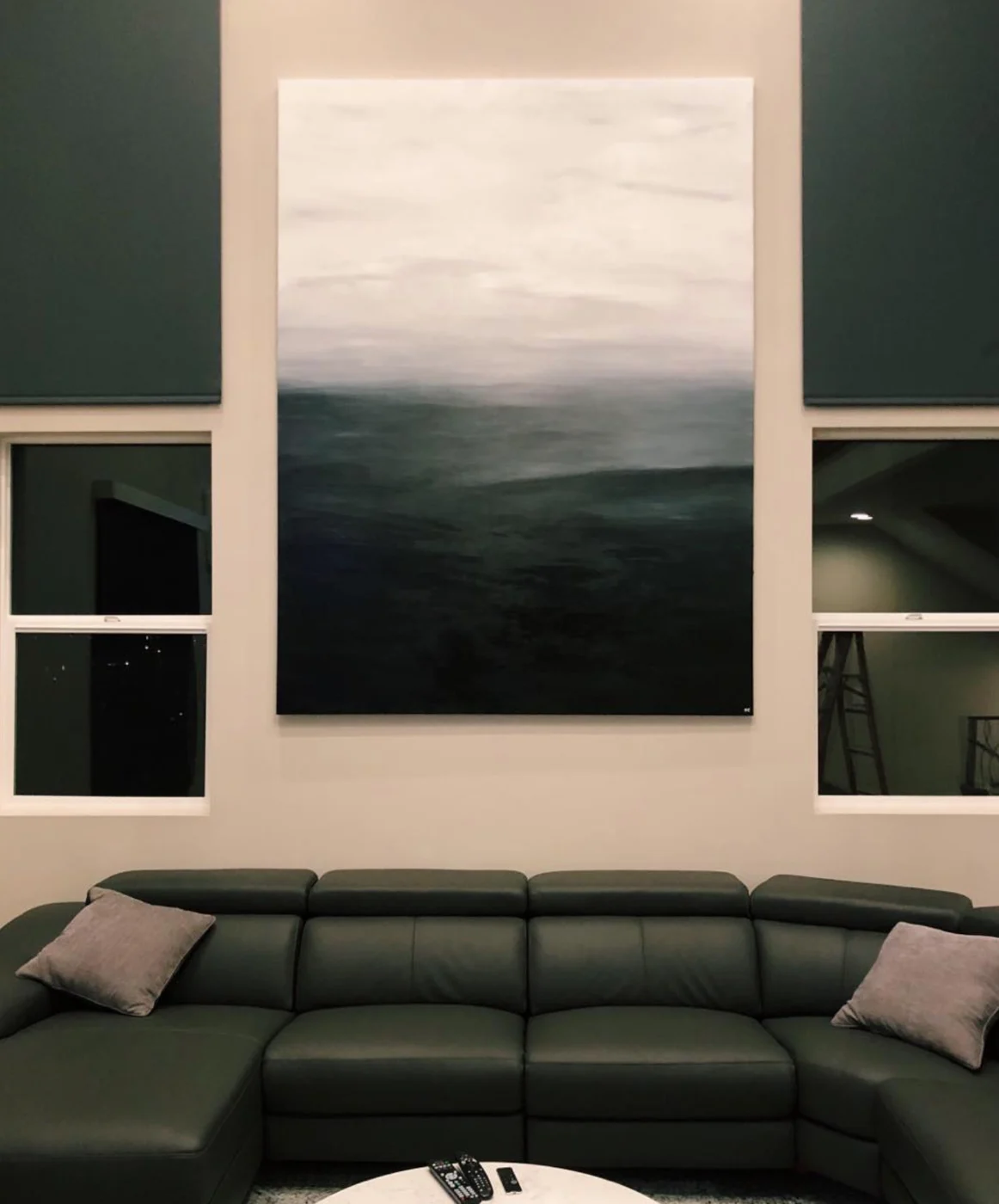 Large moody seascape painting in deep green and soft white hanging above a sofa in a Manhattan Beach home