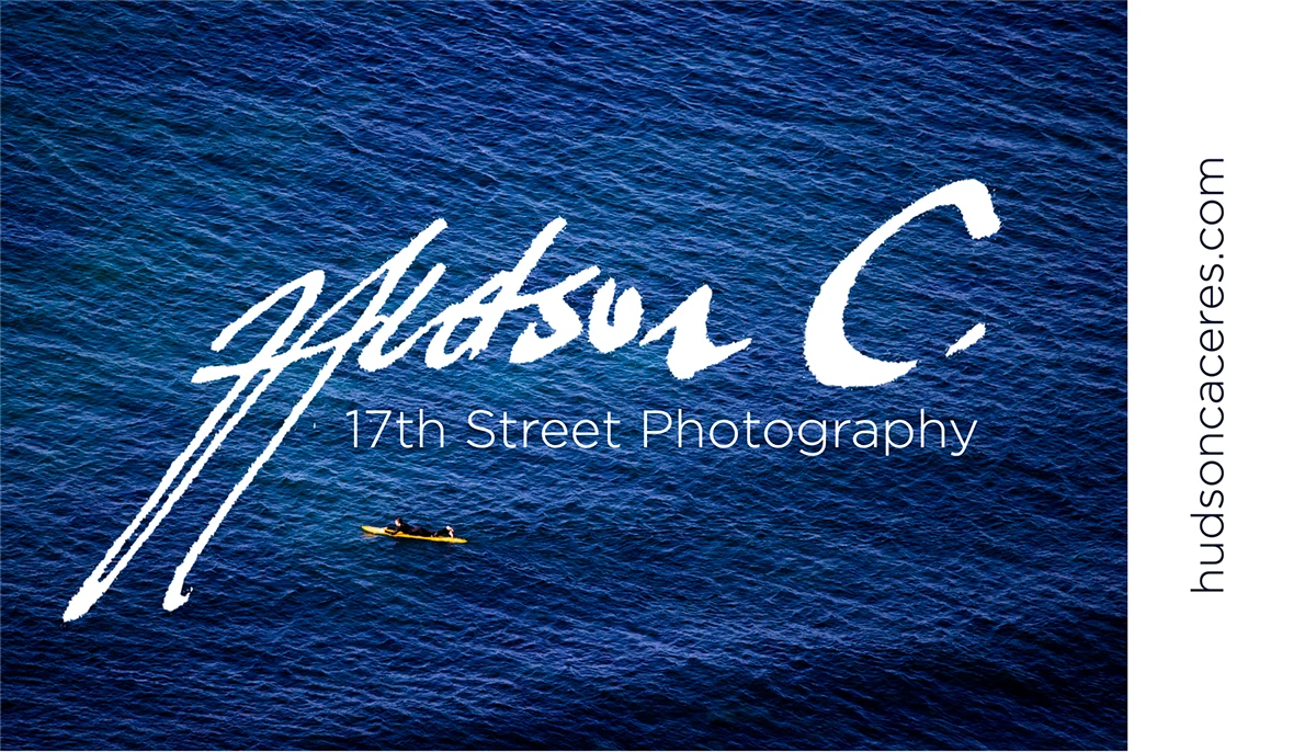 Card front: hand-signed Hudson C. logo over deep blue ocean with a lone surfer