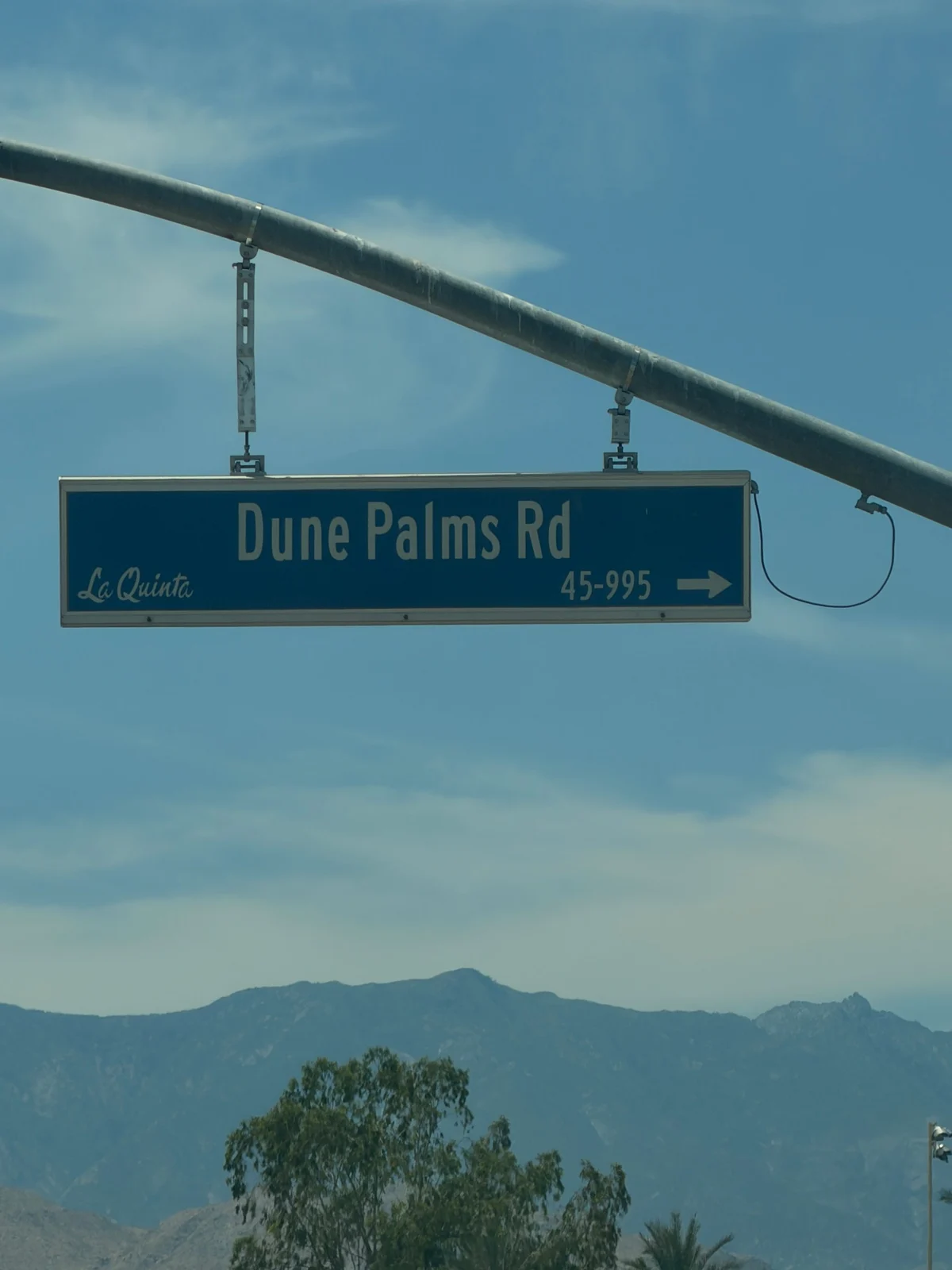 Dune Palms Rd street sign in La Quinta with mountains behind it