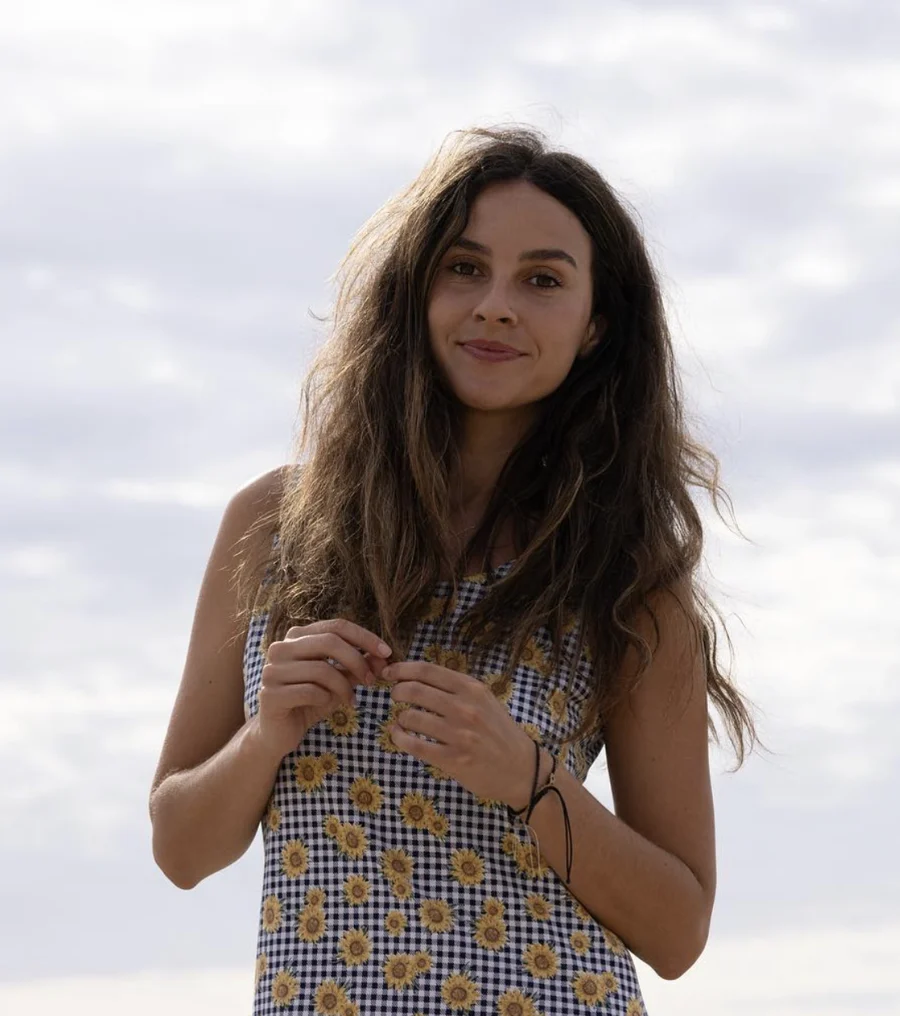Erin Caceres smiling outdoors in a sunflower gingham dress