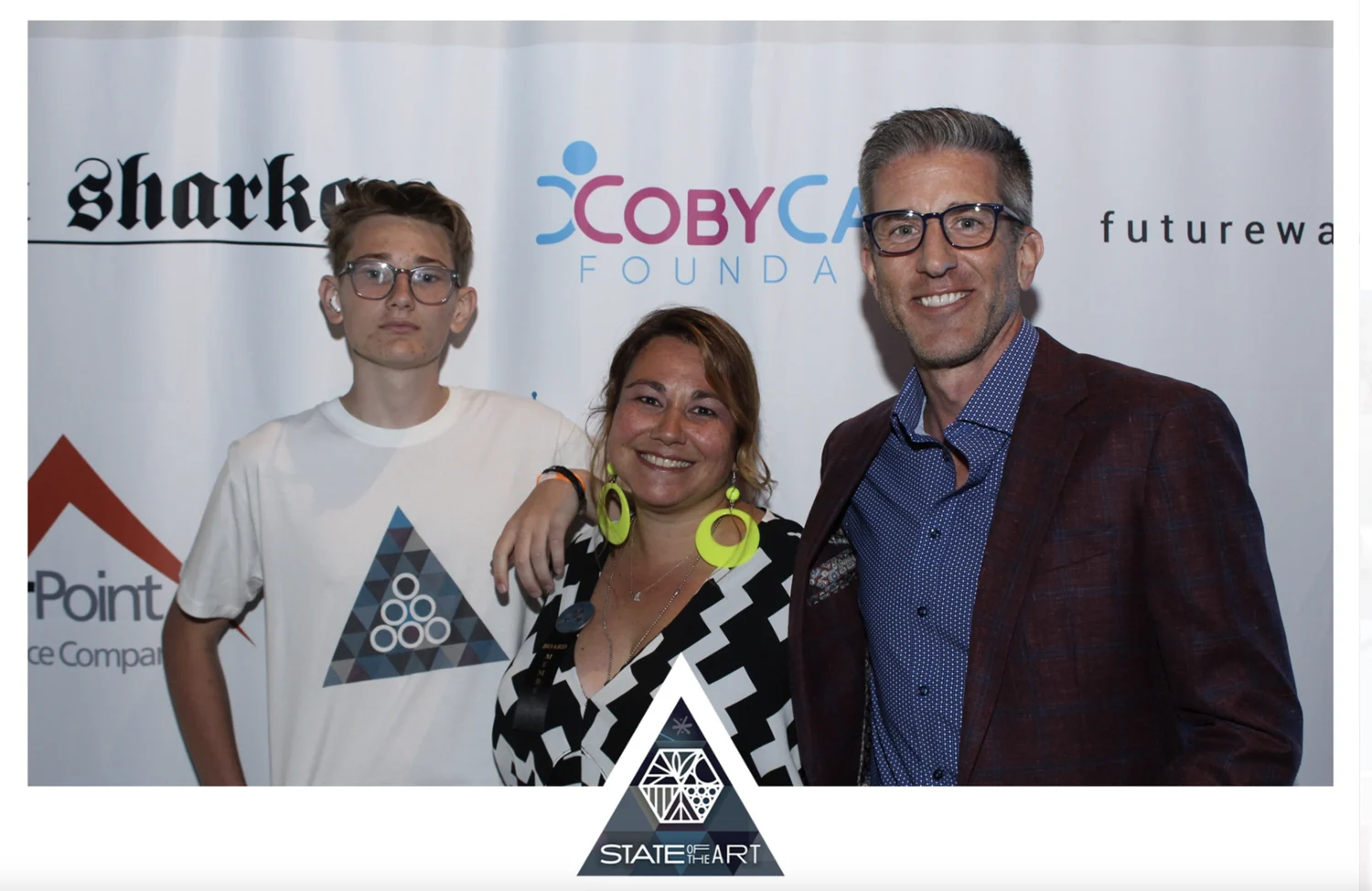 Photo booth print with the State of the Art triangle logo frame, guests posing in front of the sponsor wall
