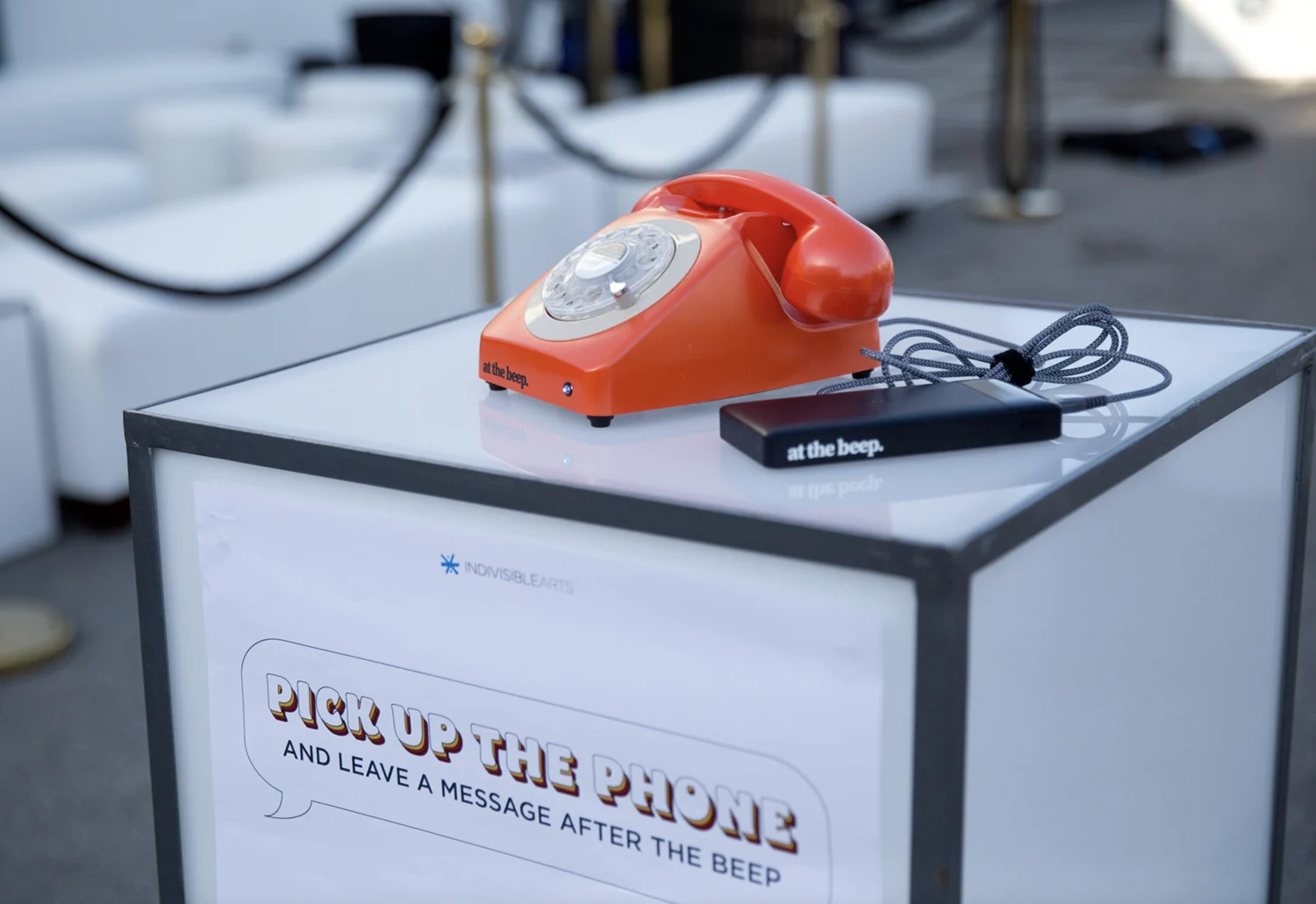 Pick Up the Phone and leave a message after the beep sign on a pedestal with an orange rotary phone